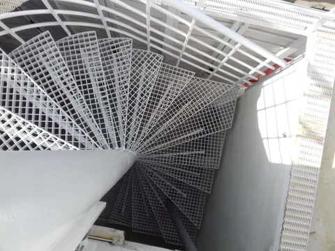 Bijelo spiralno stubište s perforiranim gazištima, pogled odozdo