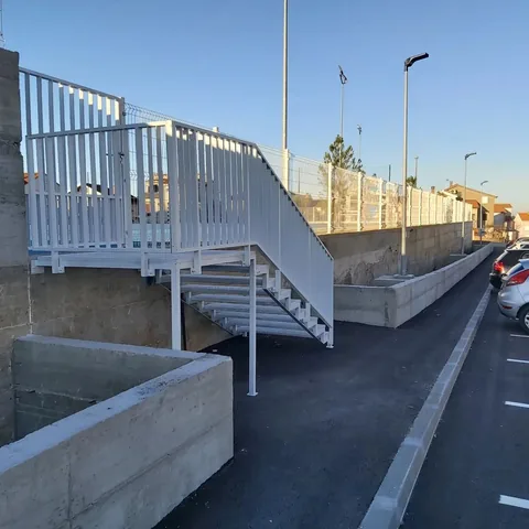 Bijelo vanjsko čelično stubište do gornjih vrata uz betonski zid