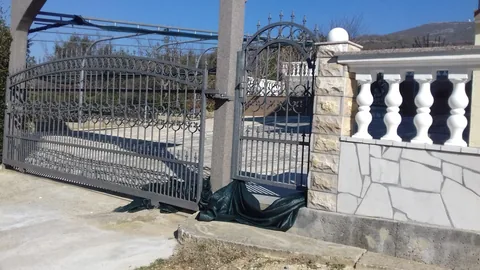 Ukrasna kovana klizna dvorišna vrata uz kameni stup