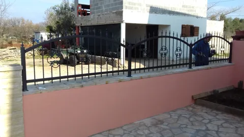 Crna metalna ograda na ružičastom dvorišnom zidu