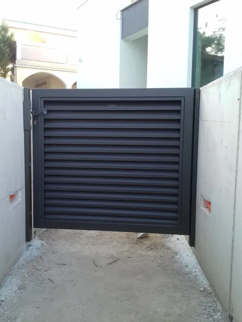 Antracitna pješačka vrata s vodoravnim lamelama između bijelih zidova