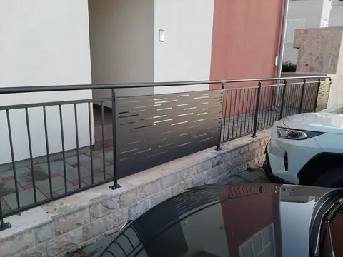 Tamna ograda s okomitim šipkama i perforiranim ispunama