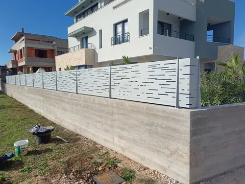 Duga svijetla ograda s vodoravnim perforacijama na betonskom zidu