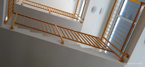 Žuta metalna ograda stubišta, pogled odozdo kroz otvor etaža