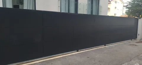 Duga puna tamna klizna vrata na betonskom prilazu
