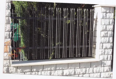 Crna ukrasna željezna ograda između kamenih stupova