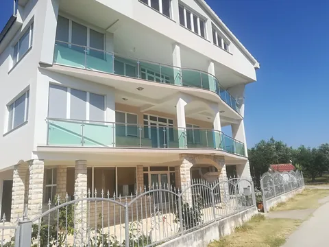 Svijetla višekatnica sa staklenim balkonima i inox uličnom ogradom
