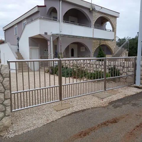 Vanjska inox vrata s okomitim šipkama ispred kuće s lukovima