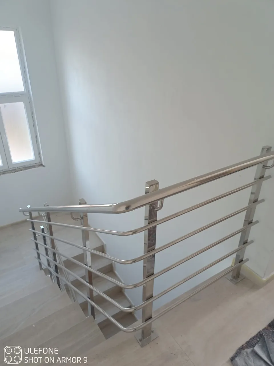 Pogled odozgo na inox ogradu stubišta i savijeni kutni rukohvat