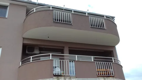 Dva zaobljena balkona s ogradama od okomitih šipki i metalnim rukohvatom