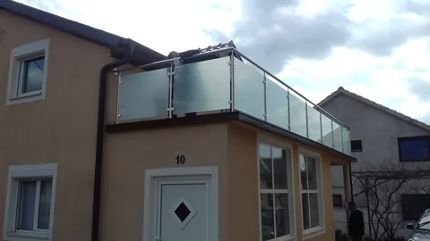 Balkon bež kuće s neprozirnim staklenim ispunama u metalnim okvirima