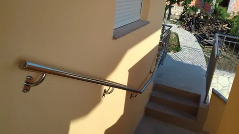 Zidni inox rukohvat na žutoj fasadi iznad vanjskih stuba