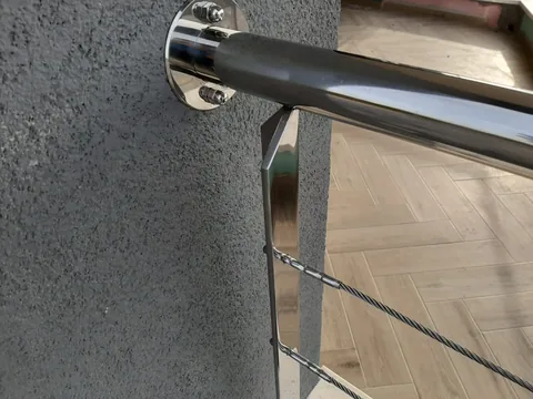 Krupni plan poliranog inox spoja rukohvata i vodoravne sajle