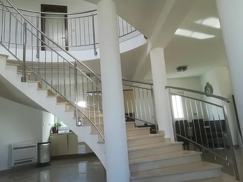 Pogled iz prizemlja na zakrivljeno stubište s okomitom inox ogradom
