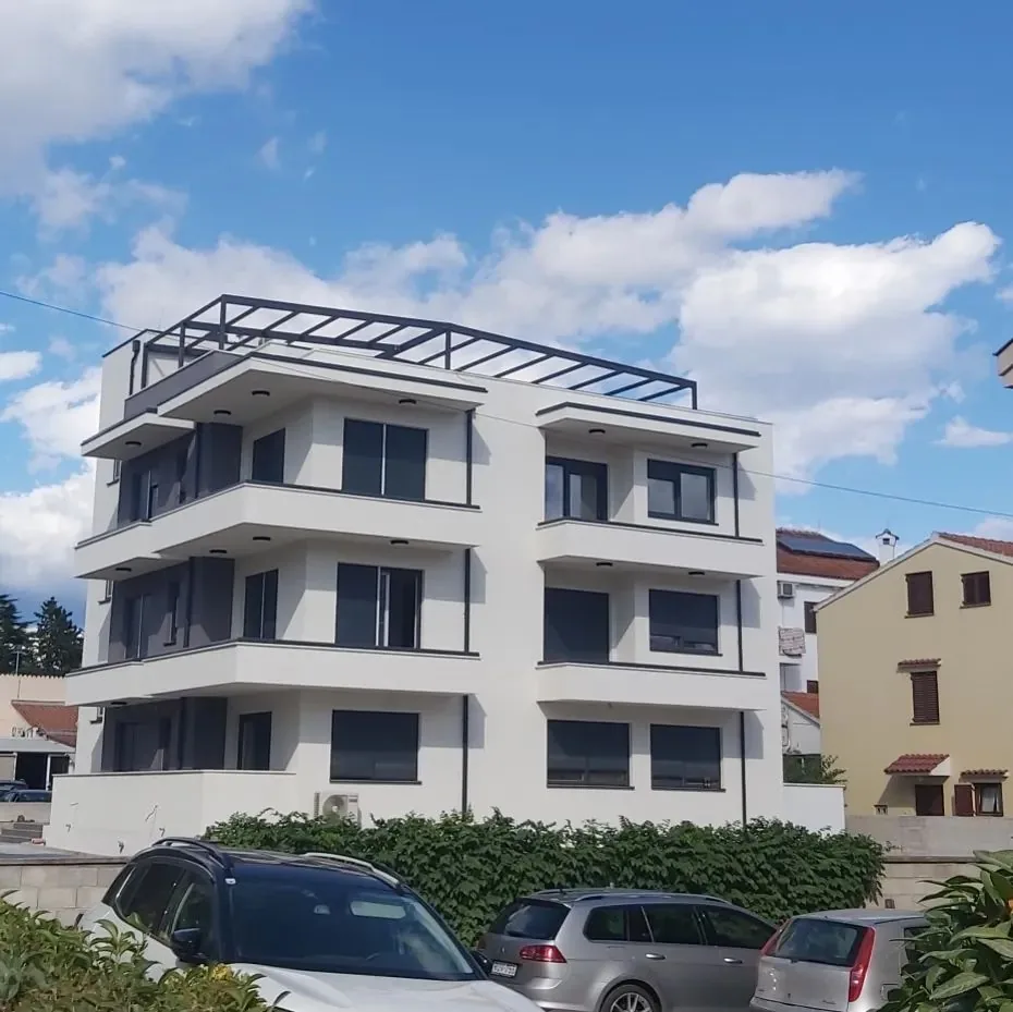 Bijela višekatnica s pravokutnom čeličnom pergolom na ravnom krovu